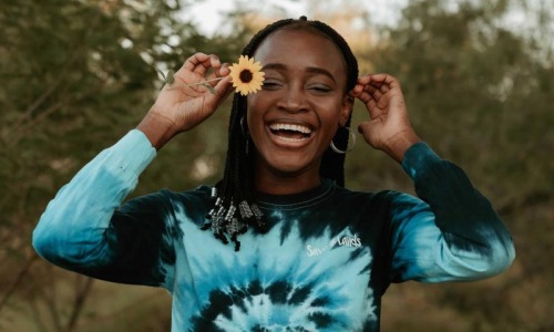 woman holds a flower in her hair in a park